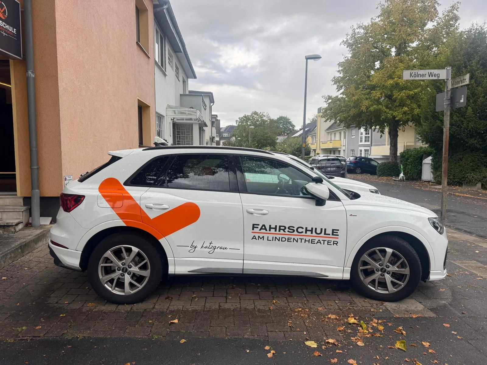 Weißes Fahrschulauto mit oranger Beklebung der Fahrschule am Lindentheater