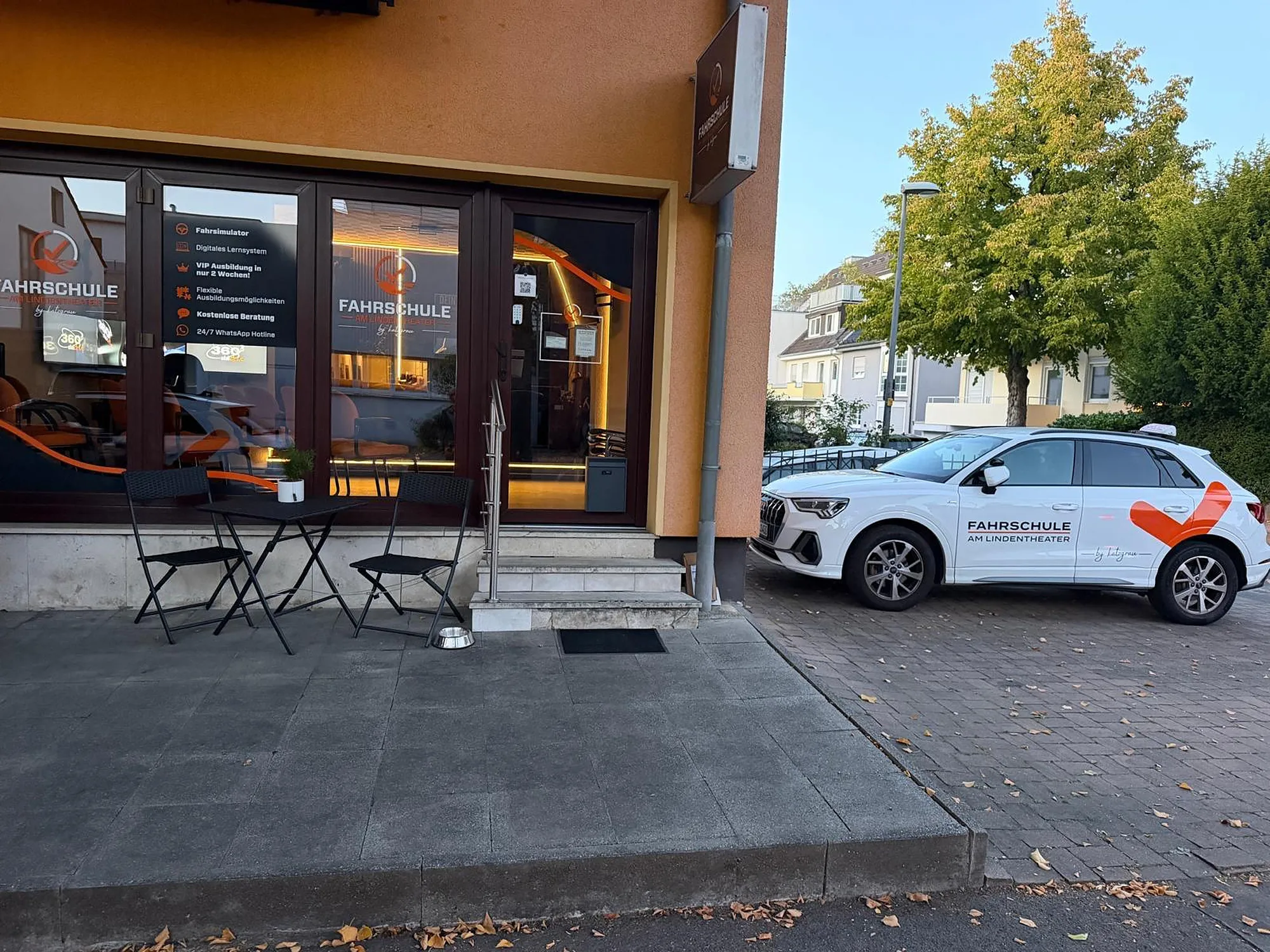 Eingang der Fahrschule in Köln-Junkersdorf mit Sitzecke und Fahrschulauto